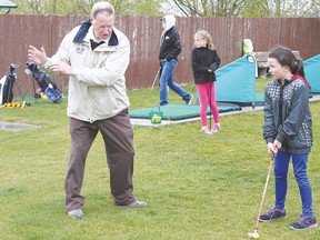 Dusty Rhodes shows Emma Kaiser, 8, how to improve her swing during a rainy day at the Vulcan Golf and Country Club driving range on May 15.