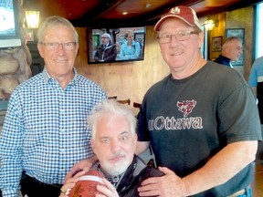 Yves Leclerc, confined to a wheelchair, strikes the QB’s pose at the U of O Hall of Fame induction party at Fathers and Sons Restaurant. Standing with him are his former Gee-Gees receivers coach Bob Swan (left) and teammate Duncan Armstrong.