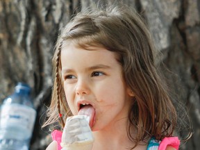 Four-year-old Sophia Vilela takes a big lick of her ice cream while resting in the shade with her dad during the free Victoria Day celebrations at Lake Ontario Park on May 18. The up-and-down weather in May is expected to give way to a typically hot summer, according to a weather expert. (Julia McKay/The Whig-Standard)