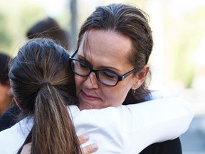 The mother of a seven-year-old transgender girl hugs supporter Marni Panas outside of the Edmonton Catholic School Board offices Tuesday. IAN KUCERAK/EDMONTON SUN/POSTMEDIA NETWORK