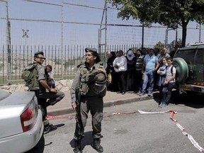 An Israeli border policewoman stands in front of passers-by at the scene of an attack in the East Jerusalem neighbourhood of A-Tur May 20, 2015.  REUTERS/Ammar Awad