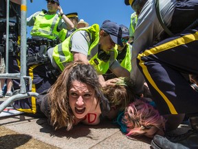 Topless pro-choice protesters are held to the ground by RCMP officers at the 'March For Life' on Parliament Hill in Ottawa on Thursday May 14, 2015. (Errol McGihon, Postmedia Network)