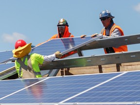 Workers for the Kingston Solar project install one of the solar panels on a rack in Zone 4 on Wednesday. (Julia McKay/The Whig-Standard)