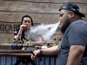 Annie Young (L) and Dan Leano smoke e-cigs at the Vape Summit 3 in Las Vegas, Nevada May 2, 2015. According to new research provided to Reuters, youngsters say that the flavors of the vaping liquids, and the "ability to do tricks" are the top two reasons they consider electronic vaping devices cool. REUTERS/David Becker
