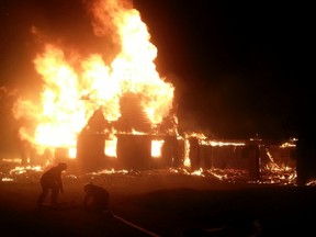 The William Cross Homestead in Chelsea burns in a fire Thursday night as Chelsea fire crews set up hose in an attempt to battle the flames. (Submitted image)