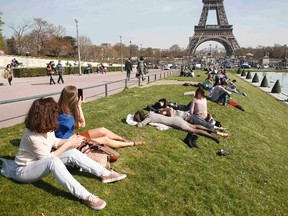 In this April 9, 2015 photo, tourists enjoy a sunny day near the Eiffel Tower in Paris. The Eiffel Tower,  which has closed to the public as workers protest a rise in aggressive pickpockets around the Paris landmark, will reopen its doors on May 22, 2015. REUTERS/Charles Platiau
