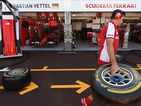 A mechanic of the Ferrari team carries a tyre in the pits ahead of practicing tyre changes on Sebastien Vettel's Ferrari formula one car on the eve of the first practice session of the Monaco Formula One Grand Prix in Monte Carlo on May 20, 2015. (AFP/PHILIPPE DESMAZES)