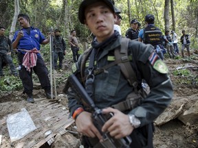 Security forces and rescue workers watch as human remains are retrieved from a mass grave at an abandoned camp in a jungle some three hundred meters from the border with Malaysia, in Thailand's southern Songkhla province. REUTERS/Damir Sagolj