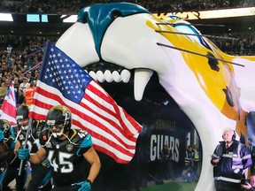Jacksonville Jaguars' Will Ta'ufo'ou carries a U.S. flag as he runs onto the field before their NFL football game against the Dallas Cowboys at Wembley Stadium in London, November 9, 2014. (REUTERS/Suzanne Plunkett)
