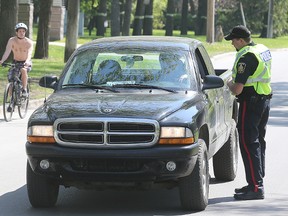 Winnipeg Police stop drivers on Wellington Crescent in Winnipeg Sunday to advise them motorists can now be fined for driving more than a block in a cycling lane on set Sunday and holiday hours. (Brian Donogh/Winnipeg Sun)