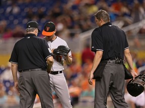 Orioles pitcher Brian Matusz was ejected by umpire Paul Emmel (left) for having a foreign substance on his arm during the 12th inning of a game against the Marlins in Miami on Saturday, May 23, 2015. (Rob Foldy/Getty Images/AFP)