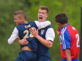 Regina Mundi?s Braeden Gee celebrates his tying goal with Jonathan Kam in the second half of the TVRA District AA boys? soccer final against Saint Andre Bessette at the North London fields on Monday. (MIKE HENSEN, The London Free Press)