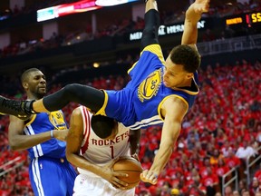 Stephen Curry of the Golden State Warriors falls over Trevor Ariza of the Houston Rockets on his way to an injury in the second quarter during Game 4 of the Western Conference finals of the 2015 NBA playoffs at Toyota Center on May 25, 2015. (Ronald Martinez/Getty Images/AFP)