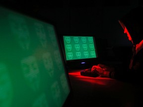 Man poses in front of on a display showing the word "cyber" in binary code, in this picture illustration taken in Zenica Dec. 27, 2014. REUTERS/Dado Ruvic