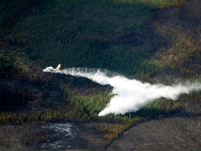 A water bomber dumps its load on the wildfire 22 km east of Slave Lake along the Old Smith Hwy near Mortonville on May 26, 2015. Many residents have been permitted to return home, but the province-wide fire ban remains in place. Alberta Wildfire Info/Postmedia Network