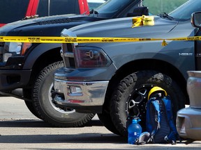 A backpack, hardhat  and water bottle sit on the ground next to two pick-up trucks as Edmonton Police Service members investigate a shooting that occurred at approximately 7:10 a.m., on Monday May 25, 2015 in the parking lot of Our Savior Lutheran Church at 18345-62B Ave., in Edmonton Alta. Tom Braid/Edmonton Sun