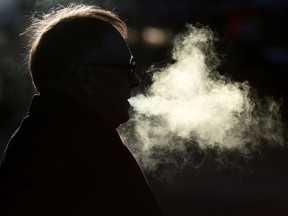 A smoker exhales while waiting to cross 109 Street at Jasper Avenue, in Edmonton Alta., on Thursday Jan. 8, 2015. David Bloom/Edmonton Sun