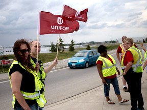Jaye Campbell and Sean Connolly from Unifor Local 27 in London, wave flags at the Toyota plant in Woodstock on Wednesday to rally support to unionize 7,500 Toyota workers at plants in Cambridge and Woodstock. (BRUCE CHESSELL, Sentinel-Review)