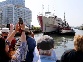 Spectators watch as the Jadran, which housed Captain John's Seafood restaurant, is towed away from Toronto's waterfront for scrap after 40 years on Thursday May 28, 2015. (Michael Peake/Toronto Sun)