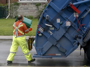 A Toronto city worker empties a green bin into a waste truck. (Jack Boland/Toronto Sun files)