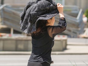 Wei Ren covers her head to avoid having her face photographed after leaving the courthouse at 361 University Ave in Toronto on Thursday May 28, 2015. (Ernest Doroszuk/Toronto Sun)