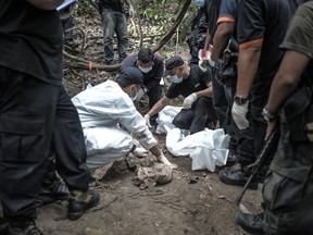 A Royal Malaysian Police forensic team handles exhumed human remains in a jungle at Bukit Wang Burma in the Malaysian northern state of Perlis this week where police found remote human-trafficking camps along the Thai border. (MOHD RASFAN/AFP photo)