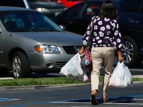A shopper carries her groceries to her car in plastic bags.

REUTERS/Mike Blake