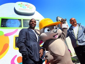 Retired Canadian Sprinter Donovan Bailey, left, with Pan Am mascot Pachi, middle, and Pan Am CEO Saad Rafi during the unveiling of the Pan Am games medal podiums at Nathan Phillips Square on May 28, 2015. (Dave Abel/Postmedia Network)