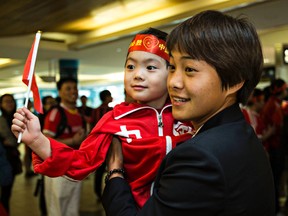 Ryan Guo, 5, poses with a Team China member as they arrive at the Edmonton International Airport (Codie McLachlan, Edmonton Sun).