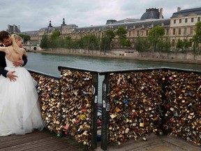 A recently-married couple from Poland, Dominika and Bartek Mieczkowski, embrace near grills covered with "love locks" on a walkway which leads to the Pont de Arts over the River Seine in Paris, France, May 31, 2015. On June 1, the bridge will be closed for a week and the padlocks which hang on the bridge will be removed by city municipal employees. A city hall campaign to save the bridges of Paris from the weight of hundreds of thousands of brass "love locks" has not checked the ardour of droves of tourists, who continue to view the City of Light as the City of Love. Iron grills lining the bridges have since 2008 been increasingly covered by brass locks purporting to symbolize the unending love of visiting tourists. 
REUTERS/John Schults