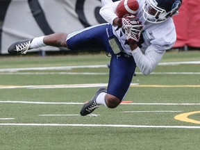 Brandon Isaac can’t quite come up with the interception during Sunday's opening of training camp for the Argos at York. Left, QB Mitchell Gale has to backhand a snap from centre. (DAVE THOMAS/TORONTO SUN)