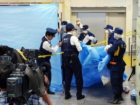 This picture taken on May 31, 2015 shows police officers inspecting a locker at the Tokyo station.  The corpse of a woman that had been stuffed in a suitcase and left in a locker at one of the world's busiest train stations went undiscovered for a month. The suitcase was abandoned in a locker at Tokyo Station in late April, but removed to the left-luggage storage room after no-one collected it. AFP PHOTO/JIJI PRESS