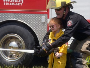 Mount Elgin captain Barry Irwin assists Eva Nigh with the fire hose Saturday at the 4th annual Mount Elgin Family Fun Day. (CHRIS ABBOTT/TILLSONBURG NEWS)