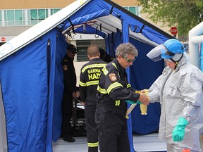 Firefighter Chris Downham is helped out of a hazmat suit during mass chemical exposure response training outside Sarnia's hospital Monday. The training was for firefighters and hospital security officials to get familiarized with each other's equipment, officials said. (Tyler Kula/Sarnia Observer/Postmedia Network)