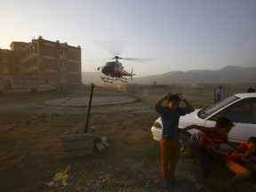 Children take cover as a helicopter carrying a victim who died after a helicopter crashed in Sindhupalchok District lands at a hospital in Kathmandu June 2, 2015. The helicopter on an earthquake relief mission crashed in high mountains in northeast Nepal on Tuesday. REUTERS/Navesh Chitrakar