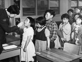 Nurse Desrochers checks a girl's throat while other children wait in line, at the Frobish Bay Federal Hostel in Iqaluit, Nunavut, in a 1959 archive photo. (Reuters)
