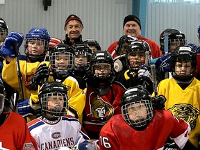Volunteers Rick Smith and Shawn Babcock, seen at the back of the photo, from the Boys and Girls Club of Kingston and Area Ice Hockey Program gather with some of the players for a group photo at the Wally Elmer Youth Centre in January 2015. (Ian MacAlpine/The Whig-Standard)