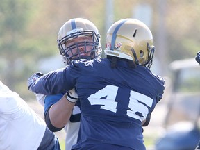 Winnipeg Blue Bombers offensive lineman Dominic Picard (l) tangles with linebacker Rodney Lamar during CFL football practice in Winnipeg, Man. Sunday, May 31, 2015.