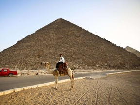A picture taken on November 9, 2014, shows a police officer riding a camel past the pyramids in Giza, on the outskirts of Cairo. Two tourism and antiquities police officers were killed near the pyramids on Wednesday. AFP Photo/Mohamed El-Shahed