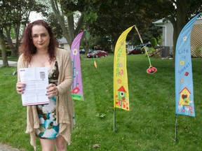 Judy Zik has placed three flags in her front yard, representative of the three community mailboxes Canada Post has notified her will be placed outside her home on Jena Crescent in London, Ont. on Monday June 1, 2015. (CRAIG GLOVER, The London Free Press)