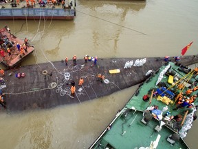An aerial view shows rescue workers standing on the sunken cruise ship Eastern Star in Jianli, Hubei province, China, June 4, 2015. China has pledged that there would be "no cover-up" of an investigation into the sinking of a cruise ship on the Yangtze River, which has left 65 people dead and over 370 missing, as angry families gathered near the rescue site to demand answers. President Xi Jinping convened a special meeting of the ruling Communist Party's Politburo Standing Committee, the apex of power in the country, on Thursday to discuss the disaster, state news agency Xinhua said. REUTERS/Stringer