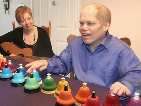 Accompanied by Shera Lumsden, left, director of MusicMates, a program of music instruction for people with special needs, client Greg Robson plays the desk bells at his home in Kingston. Robson will be the opening act for a fundraising concert. Michael Lea/The Whig-Standard/Postmedia Network.(Michael Lea/The Whig-Standard)