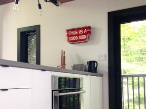 A chrome faucet provides pop while white subway tile is flanked by a storage unit and fridge freezer hidden behind an Ikea door.