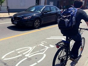 Controversial “sharrows” line Wellington St. between Parkdale and Holland Aves. as a cyclist and car cross paths Thursday, June 4, 2015. The city hopes the sharrows encourage drivers to share the road.
ERROL MCGIHON/Ottawa Sun