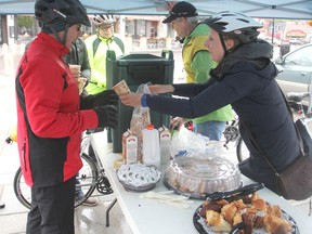 Cycling ambassador Simone Brechin, right, provides a light breakfast to cyclist Don Cowell as he stops at the Cycle Kingston tent set up in the Springer Market Square in Kingston this week. (Michael Lea/The Whig-Standard)