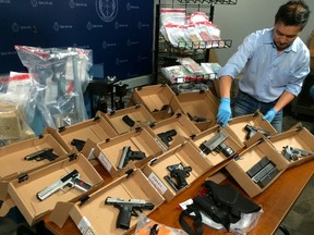 Toronto Police held a news conference Thursday, June 5, 2015, to reveal details of Project Pharaoh, an investigation targeting a mid-level street gang known as Monstarz. Const. Victor Kwong arranges the firearms, drugs and cash seized during Pharaoh. (CHRIS DOUCETTE/Toronto Sun)