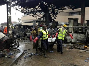 Rescue workers carry a corpse from the remains of a petrol station that exploded overnight killing around 90 people in Accra, Ghana, June 4, 2015. Many people were seeking shelter at the petrol station from torrential rain, on Wednesday night, the fire brigade said. The blast was caused by a fire that erupted at a nearby lorry terminal then spread to the petrol station and other buildings, fire brigade spokesman Prince Billy Anaglate said. REUTERS/Matthew Mpoke Bigg