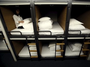 A woman sits inside a one man capsule bed unit called a "pod" inside a hotel at Grids at the Akihabara shopping district in Tokyo, Japan, May 19, 2015. REUTERS/Yuya Shino