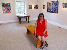 Ariel Lyons sits with her artwork on display in the Gallery in the Grove. Her joint show with Heidi Berger, "Tales of Two Women" opens Sunday.  Photo taken at Sarnia, Ontario on Thursday, June 4, 2015 (Chris O'Gorman, The Observer)