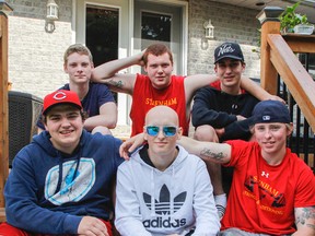 As their new tattoos say, Family Fights Together, which is what Jake Jarvis, back left, Ryan Rettie, Adrian Schwarz, Chad Campbell, and Shayne Jarvis have done for Sam Eastman, centre, who is battling non-Hodgkins lymphoma. The guys pose for a photo at Rettie's home in Inverary, Ont. on Friday June 5, 2015. Julia McKay/The Kingston Whig-Standard/Postmedia Network